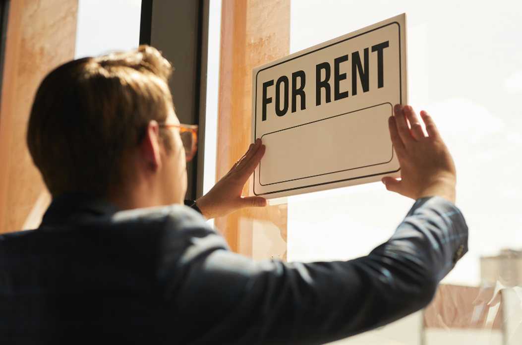 Man hanging for rent sign in window